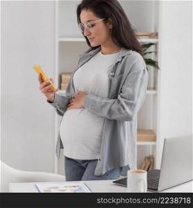 side view pregnant woman home with laptop smartphone