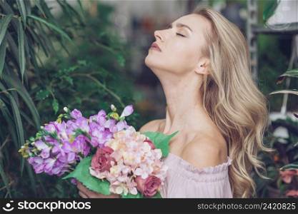 side view relaxed young woman standing garden holding colorful flower bouquet