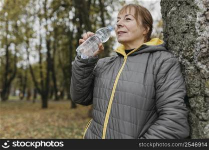 side view senior woman drinking water after working out outdoors