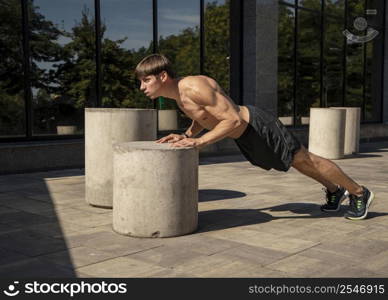 side view shirtless man doing push ups outdoors