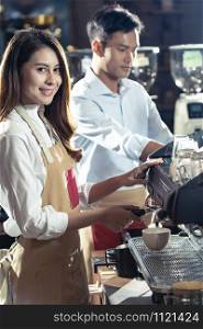 Side view shot of a female barista making a cup of coffee with other barista working in background