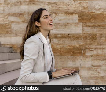 side view smiley businesswoman with smartwatch working laptop outdoors