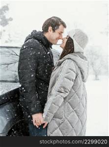 side view smiley couple kissing snow while road trip