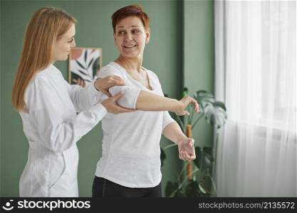 side view smiley elder woman covid recovery doing physical exercises with nurse