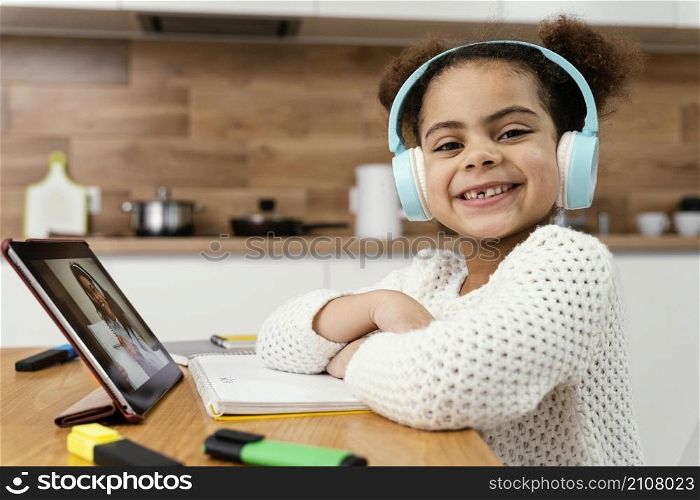 side view smiley little girl during online school with tablet headphones