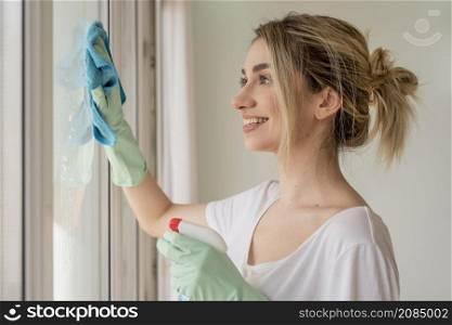 side view smiley woman cleaning window