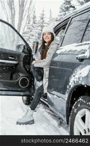 side view smiley woman enjoying snow while road trip having warm drink