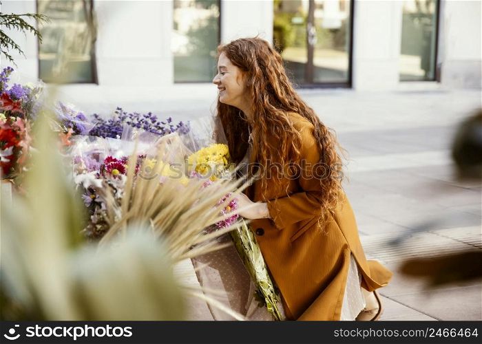 side view smiley woman getting spring flowers outdoors