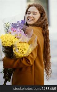 side view smiley woman holding spring flowers bouquets