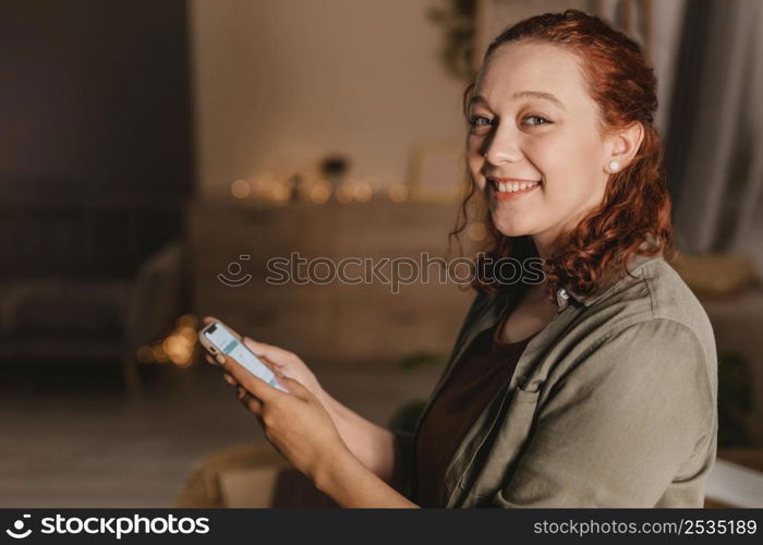 side view smiley woman home using her smartphone