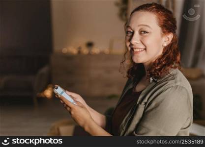 side view smiley woman home using her smartphone