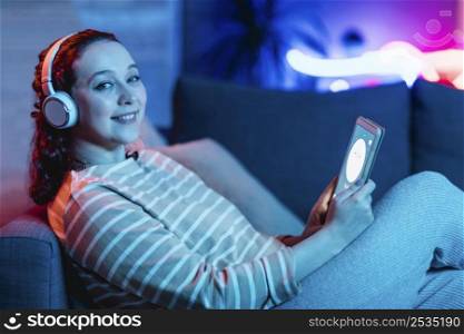 side view smiley woman using tablet headphones home