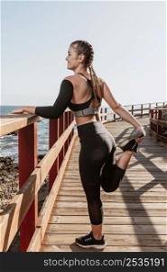 side view sporty woman stretching by beach