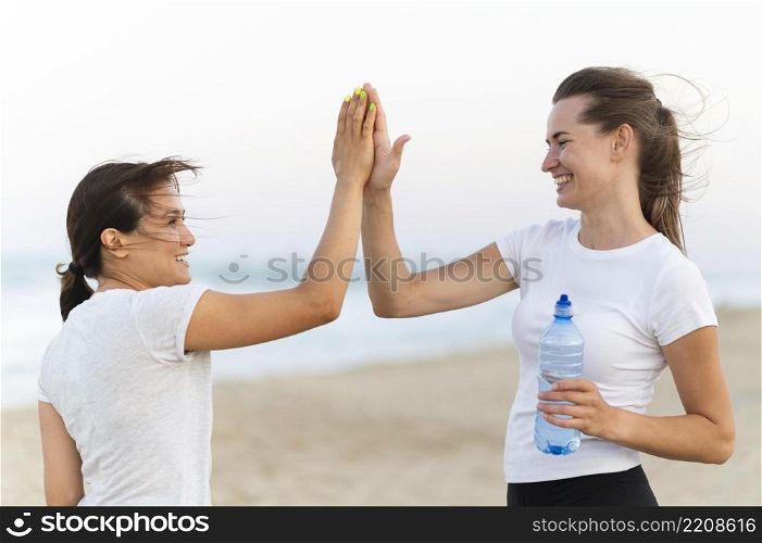 side view two women high fiving each