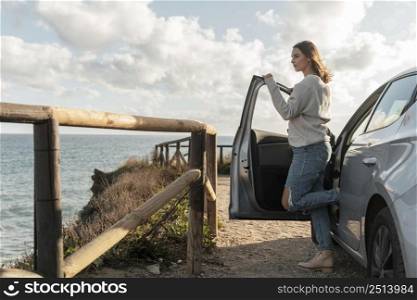 side view woman admiring beach view from her car