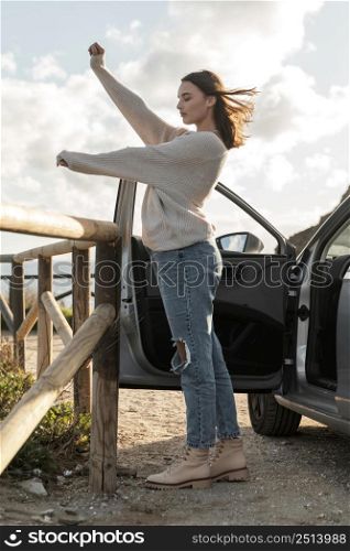 side view woman enjoying beach breeze while car