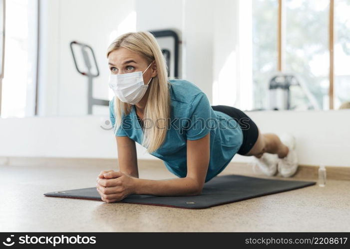 side view woman exercising gym with medical mask during pandemic