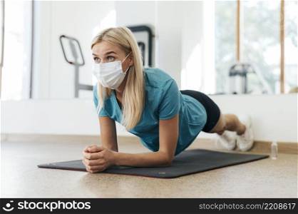 side view woman exercising gym with medical mask during pandemic