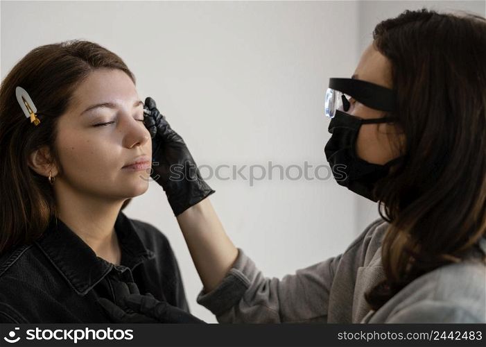side view woman getting eyebrow treatment by beautician
