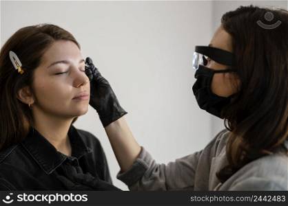 side view woman getting eyebrow treatment by beautician
