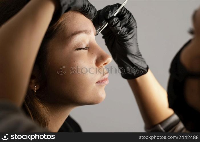 side view woman getting her eyebrows done by specialist
