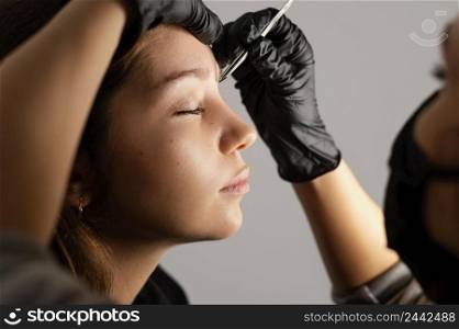 side view woman getting her eyebrows done by specialist