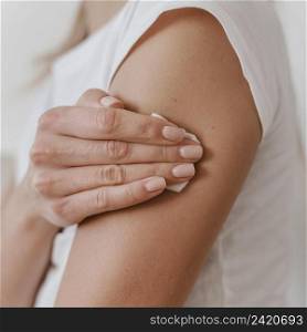 side view woman holding her arm after getting her vaccine