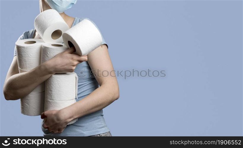 side view woman holding many toilet paper rolls while wearing medical mask. High resolution photo. side view woman holding many toilet paper rolls while wearing medical mask. High quality photo