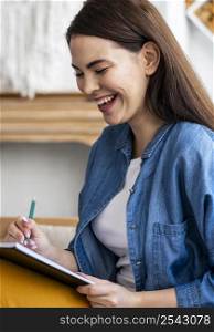 side view woman laughing while writing diary