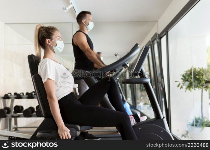 side view woman man gym with medical masks