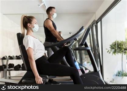 side view woman man gym with medical masks