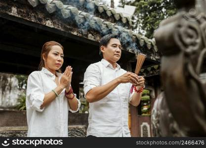 side view woman man praying temple with burning incense