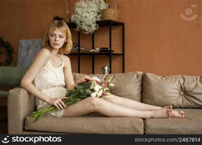 side view woman posing sofa while holding bouquet spring flowers