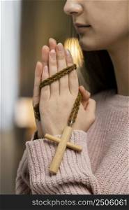 side view woman praying with wooden cross