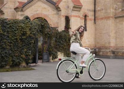 side view woman reaching her hand out while riding her bicycle