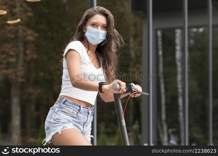 side view woman riding electric scooter while wearing medical mask