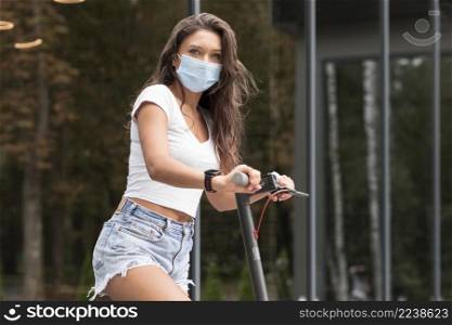 side view woman riding electric scooter while wearing medical mask
