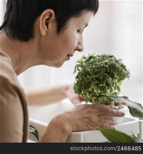 side view woman smelling indoor plant