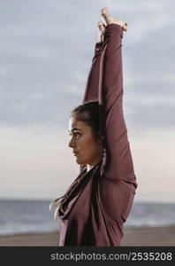 side view woman stretching by beach 2