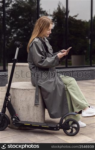side view woman using her smartphone electric scooter