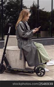 side view woman using her smartphone electric scooter