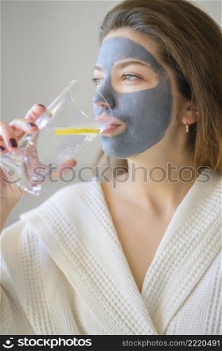 side view woman with face mask drinking water with lemon
