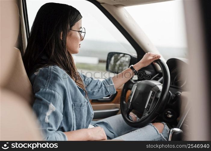 side view woman with glasses traveling alone by car