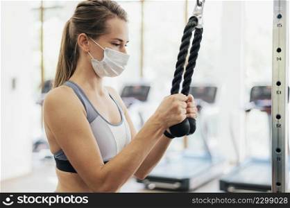 side view woman with medical mask exercising gym during pandemic