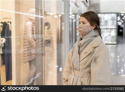 side view woman with medical mask window shopping