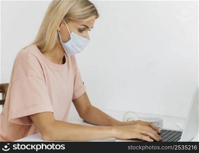 side view woman with medical mask working from home during pandemic