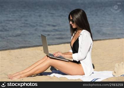 side view woman working beach with laptop