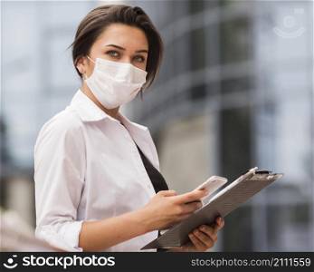 side view woman working during pandemic with smartphone notepad