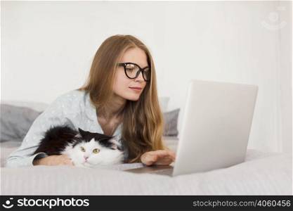 side view woman working laptop from home pajamas with cat