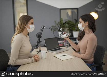 side view women with medical masks broadcasting together radio
